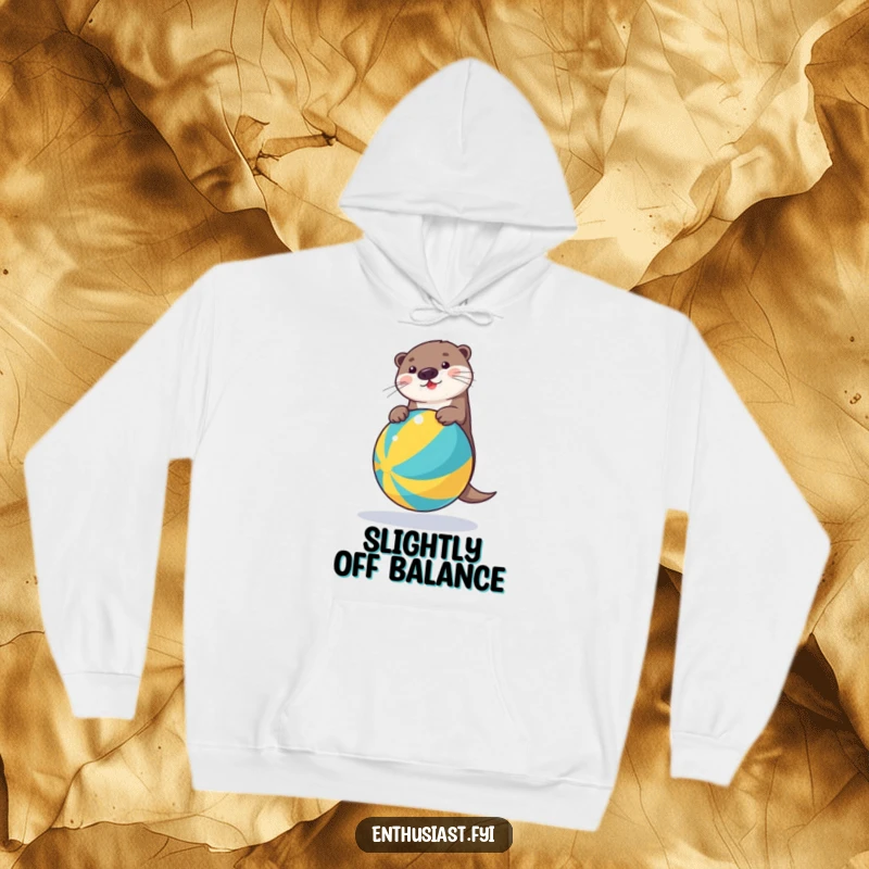 Funny hoodie depicting a cheerful otter skillfully balancing on a colorful beach ball, radiating playful energy and warmth.